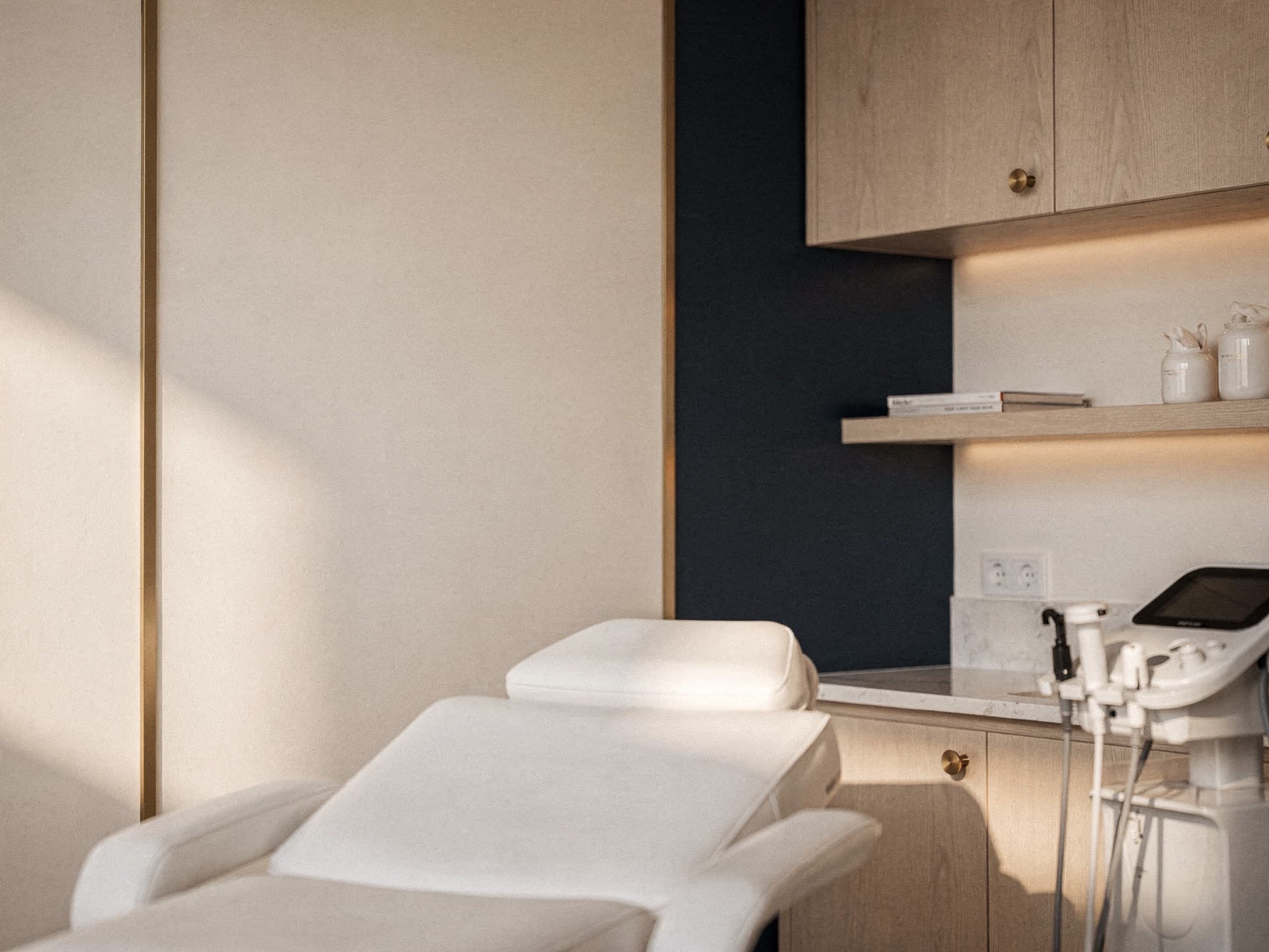 Ambiente editorial premium de consultório de cirurgia plástica, escrivaninha de nogueira, luminária de latão e escultura de mármore sobre a mesa